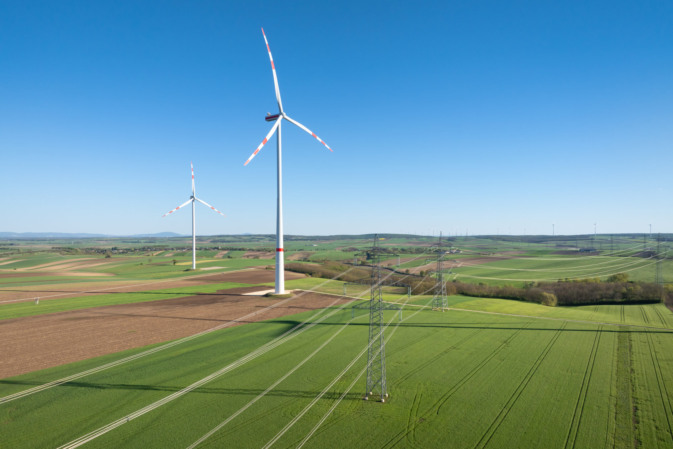 Aufnahme des Windparks Loidesthal, man sieht Windräder und Strommasten auf Feldern.
